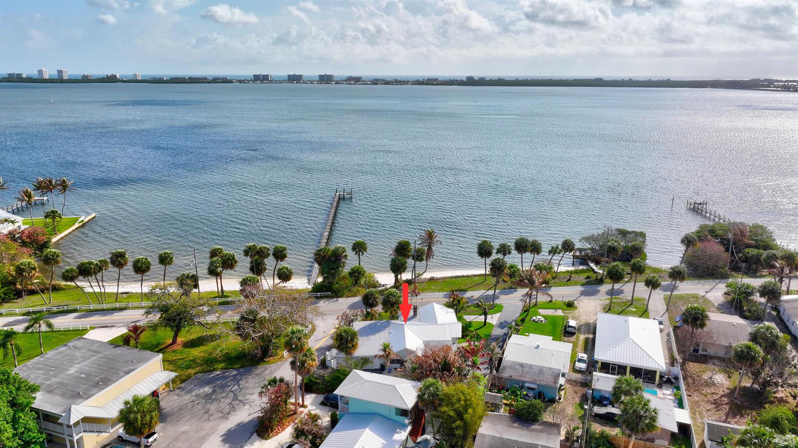 An aerial view shows a coastal house with a metal roof near a waterfront — 4490 NE Indian River Drive, Jensen Beach FL 34957, JENSEN BEACH, FL