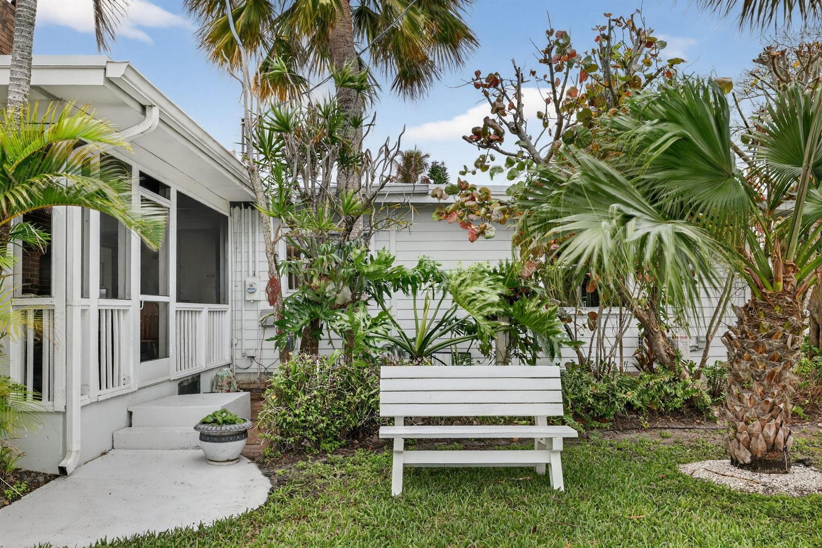 A single-story house with light siding, a brick chimney, and palm trees in the yard — 4490 NE Indian River Drive, Jensen Beach FL 34957, JENSEN BEACH, FL