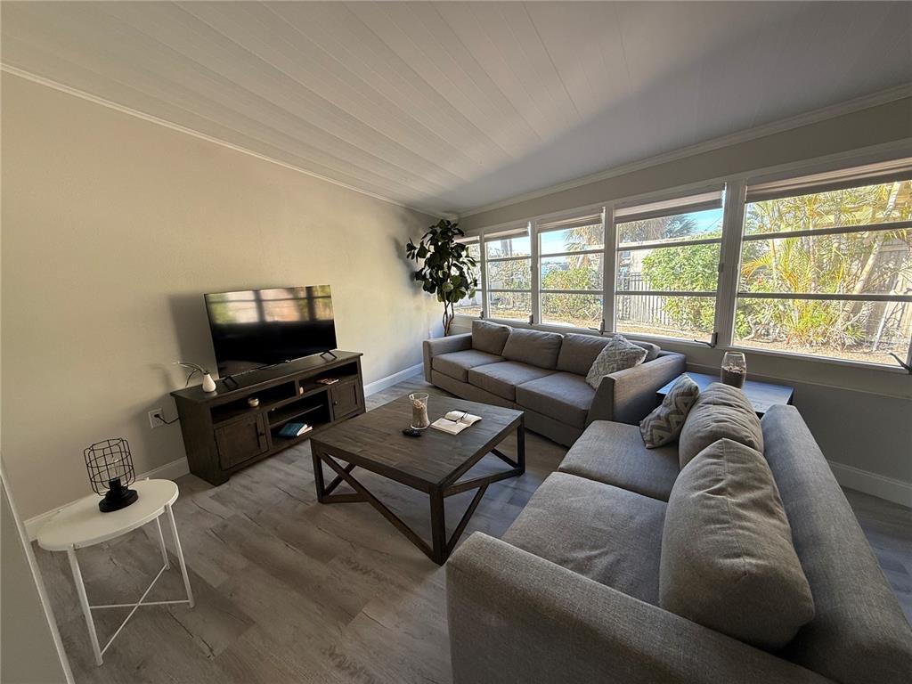 A living room features gray sofas, a dark wood coffee table, and light wood flooring — 6407 1ST PALM POINT, ST PETE BEACH, FL