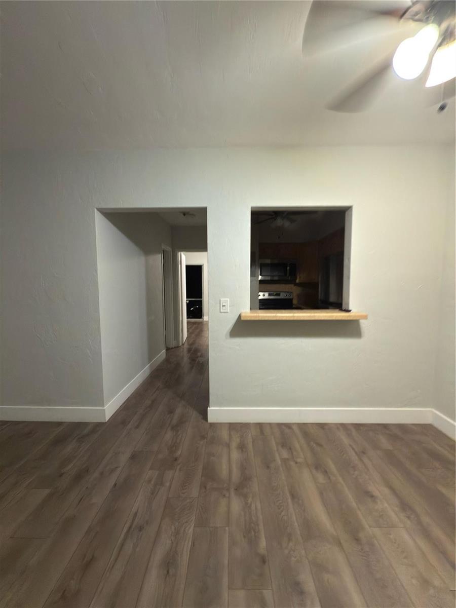 A room with wood-look flooring, a pass-through window to the kitchen, and a hallway — 600 Layne Boulevard # 117, Hallandale Beach FL 33009, HALLANDALE BEACH, FL