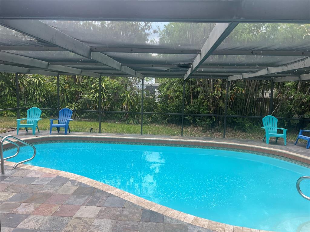 A swimming pool with a screen enclosure and patio chairs sits in a backyard — 226 DELMAR AVE, SARASOTA, FL