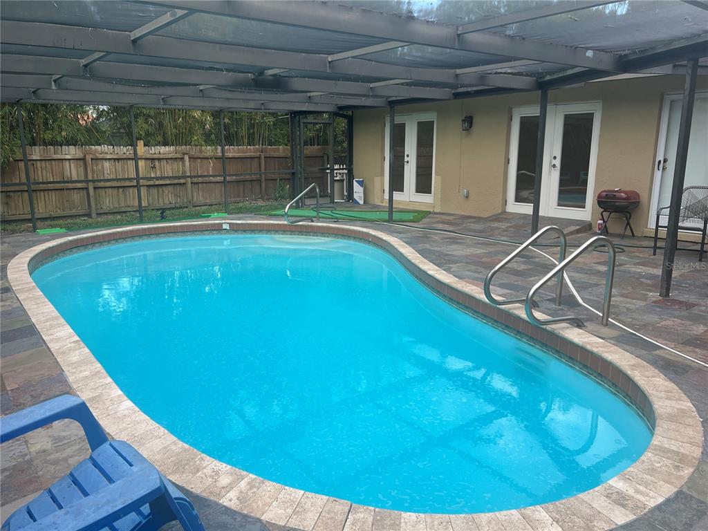 A screened-in patio features a kidney-shaped swimming pool with a brick paver coping — 226 DELMAR AVE, SARASOTA, FL