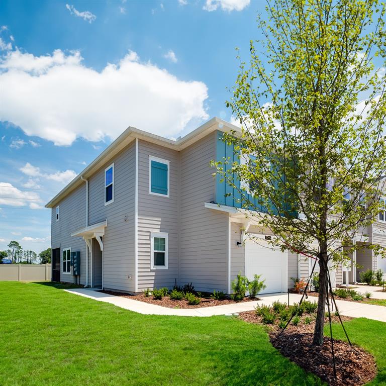 A two-story townhouse with light gray siding, a white garage, and a small front lawn — 3868 SE 36TH LANE, OCALA, FL