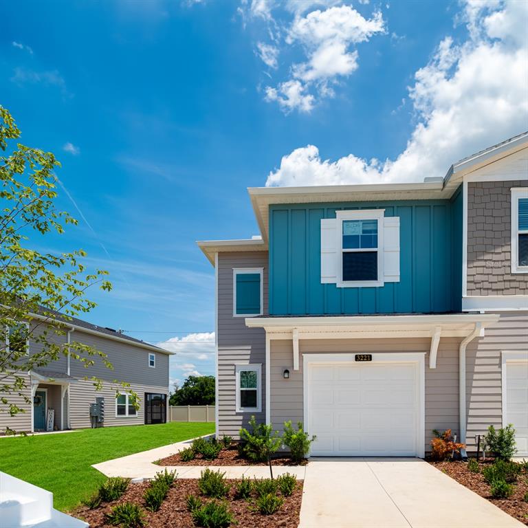 A two-story townhouse exterior features blue vertical siding, gray horizontal siding, and a white garage — 3868 SE 36TH LANE, OCALA, FL