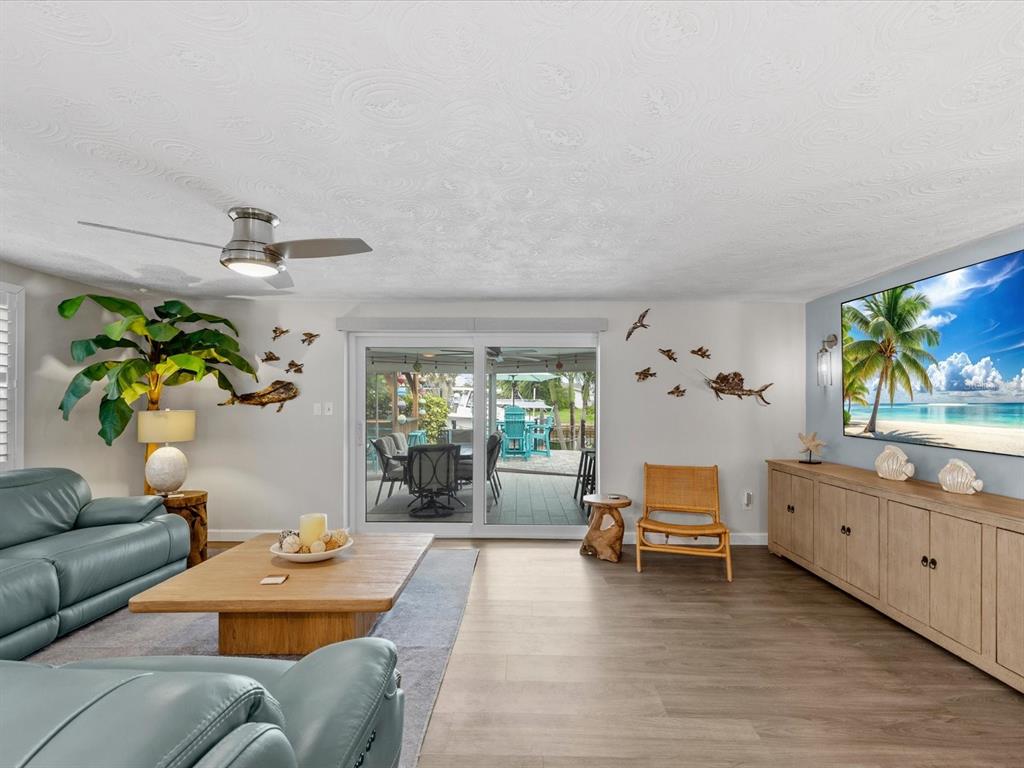A living room features a blue leather sofa, wood coffee table, and sliding glass patio doors — 4911 POMPANO DRIVE, NEW PORT RICHEY, FL