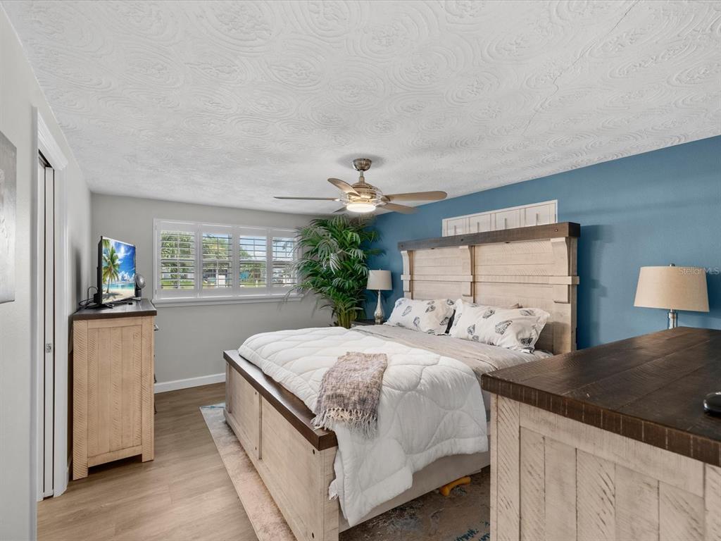A bedroom features a wooden bed frame, a blue accent wall, and a ceiling fan — 4911 POMPANO DRIVE, NEW PORT RICHEY, FL