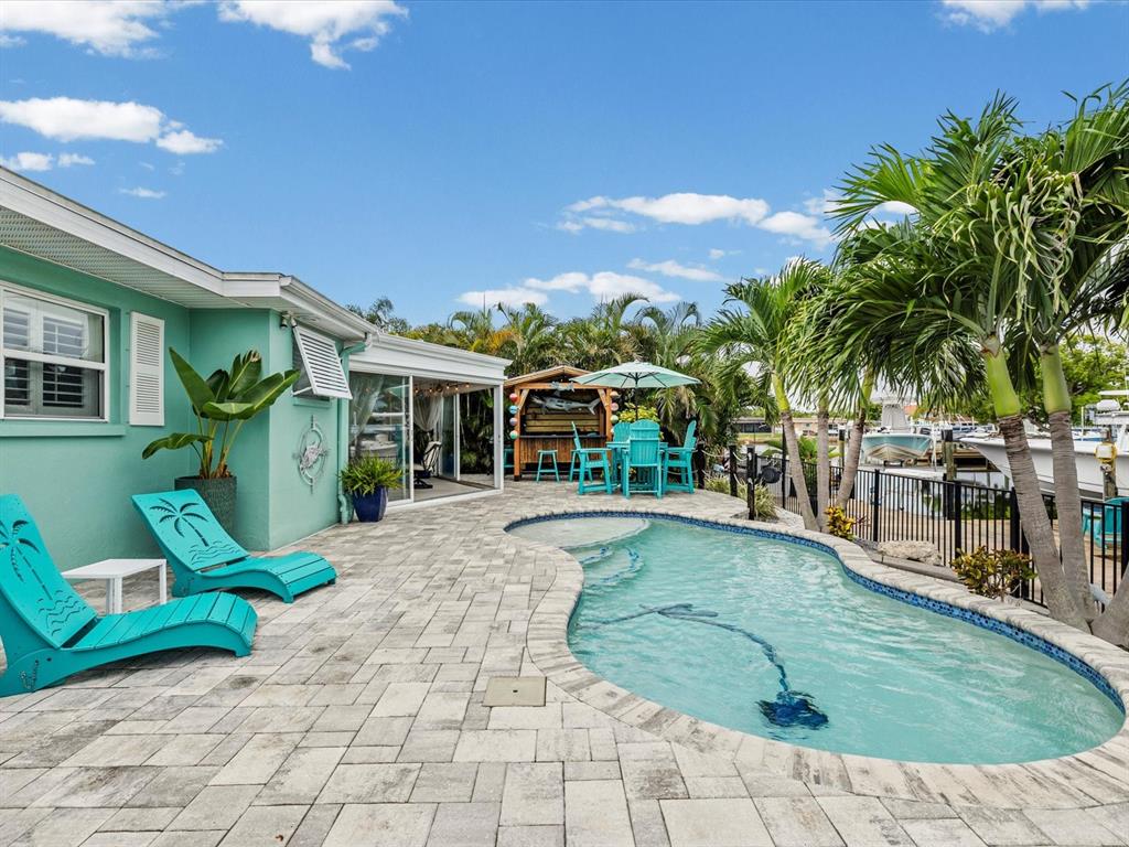 A turquoise house exterior features a patio with lounge chairs and a swimming pool — 4911 POMPANO DRIVE, NEW PORT RICHEY, FL