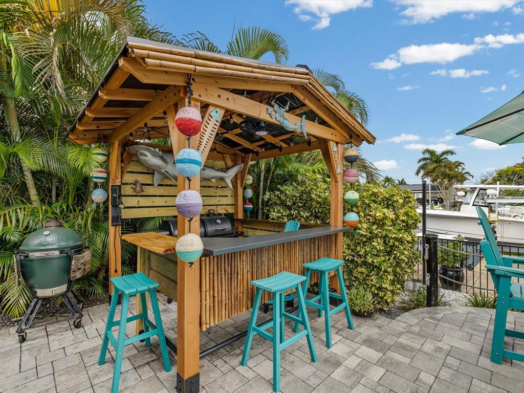 An outdoor tiki bar with a wooden structure, bar stools, and a grill on a patio — 4911 POMPANO DRIVE, NEW PORT RICHEY, FL
