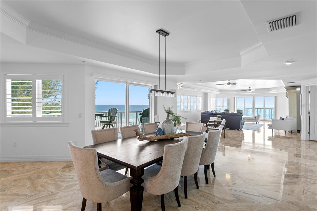 A dining area with a wooden table and chairs overlooks the ocean through sliding doors — 19730 GULF BOULEVARD UNIT 400, INDIAN ROCKS BEACH, FL