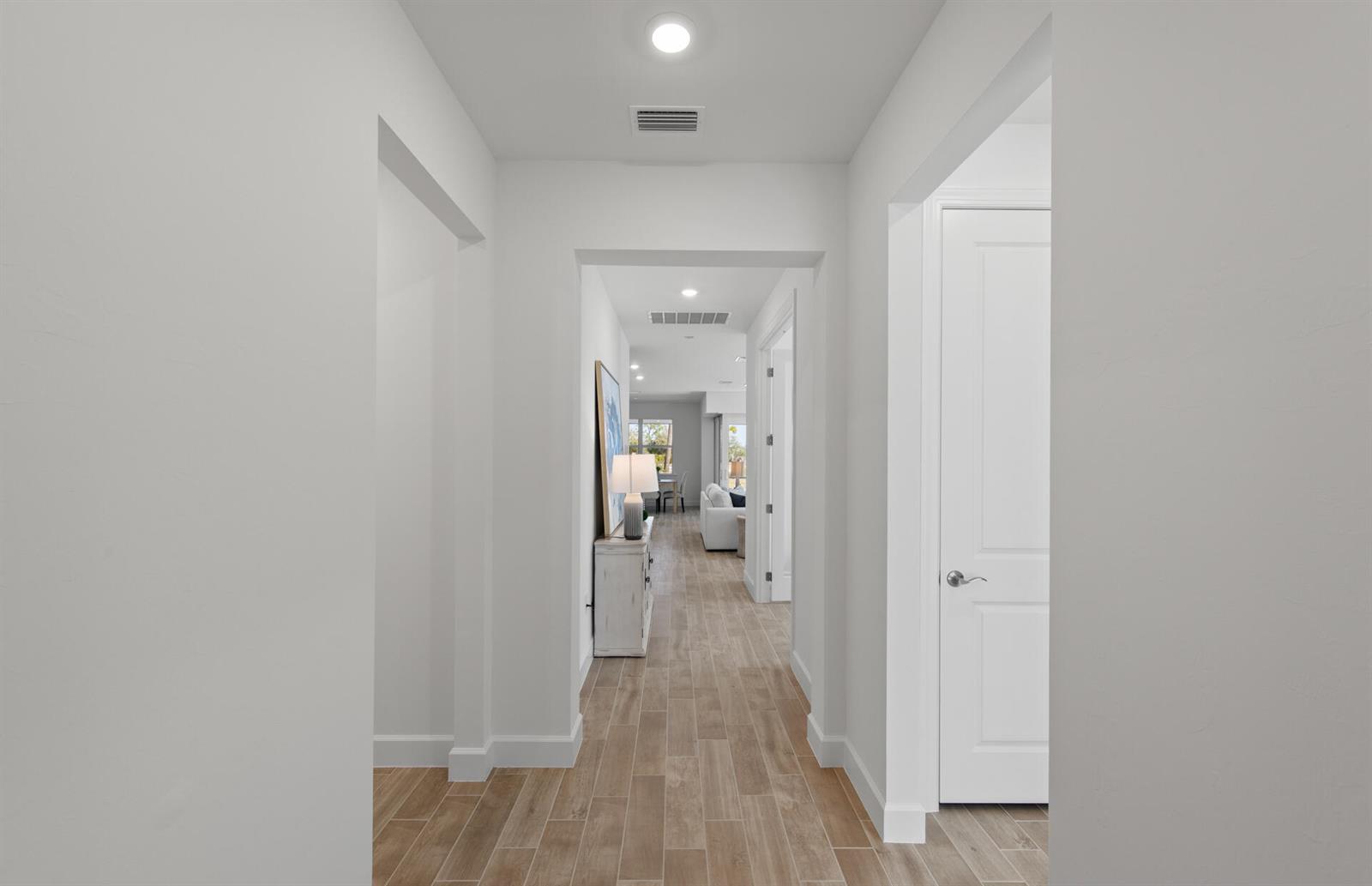 A bright hallway with light wood-look tile flooring leads toward an open living area — 12584 Quartz Drive, FL 33920, FL