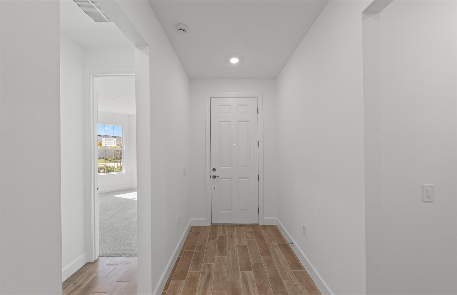 A white-walled entryway features wood-look tile flooring and a door leading to a carpeted room — 12584 Quartz Drive, FL 33920, FL