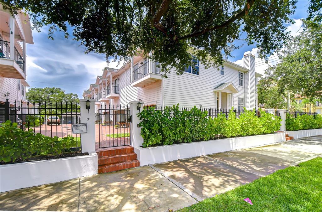 A white multi-story building with balconies sits behind a black metal fence and hedge — 113 BOSPHOROUS AVENUE UNIT 5, TAMPA, FL