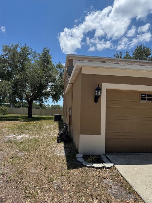 The side view of a house shows a garage, exterior wall, and a grassy yard — 18006 BIRDWATER DRIVE, TAMPA, FL