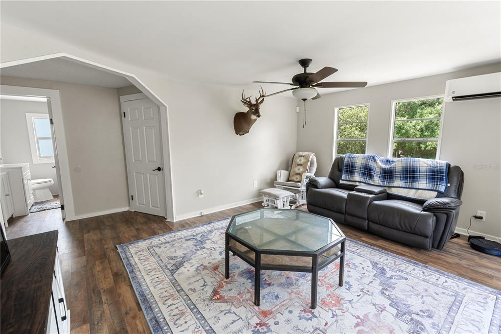 A living room features wood-look flooring, a gray sofa, a deer mount, and a ceiling fan — 301 WEAVER AVENUE, LAKE WALES, FL