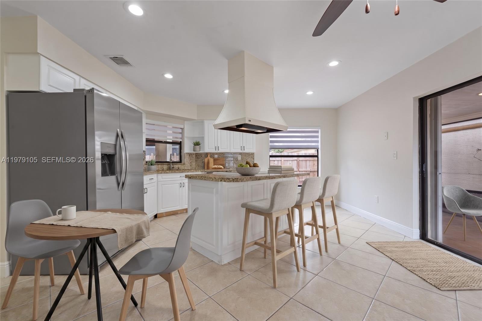 A kitchen features white cabinets, granite countertops, a center island with bar stools, and tile flooring — 536 SW 88th Ct, Miami FL 33174, MIAMI, FL