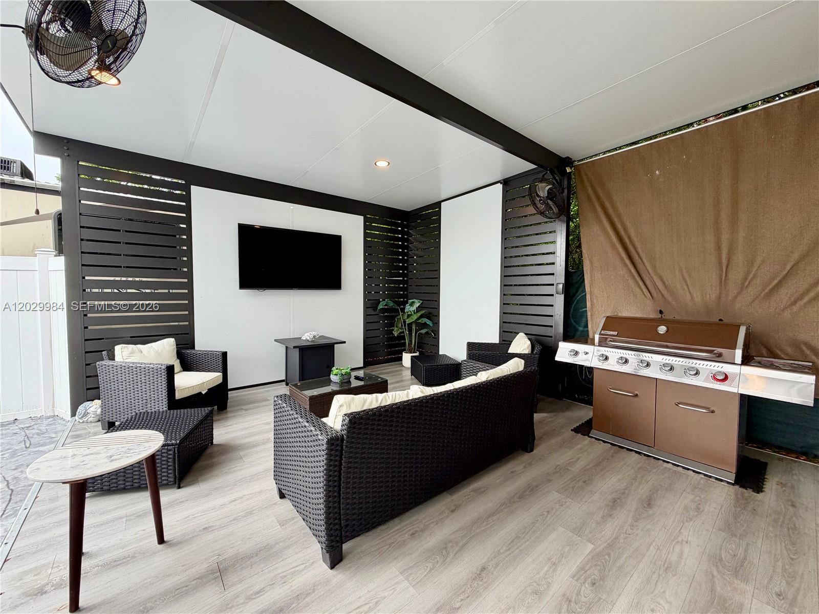 An outdoor covered patio features a television, wicker furniture, and a stainless steel grill — 325 Calusa St #122, Key Largo FL 33037, KEY LARGO, FL