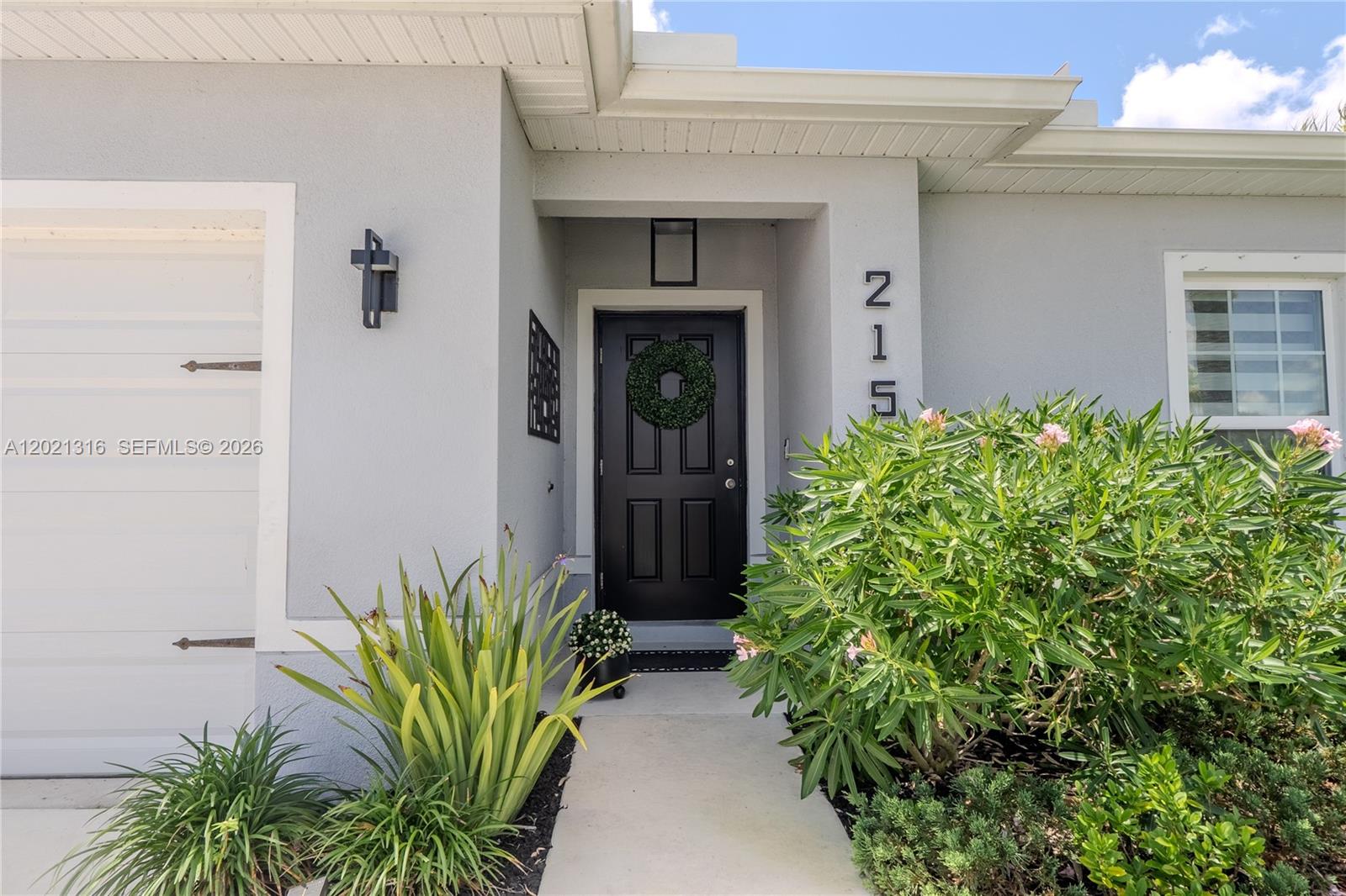 A gray house exterior features a black front door, a wreath, and a walkway — 215 Raspberry Rd, Fort Pierce FL 34981, FORT PIERCE, FL