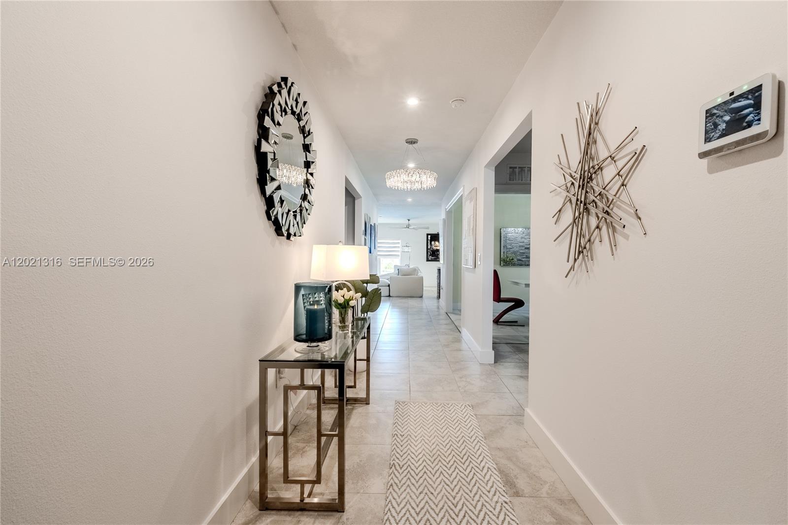 A hallway features a glass console table, wall art, and a crystal chandelier — 215 Raspberry Rd, Fort Pierce FL 34981, FORT PIERCE, FL