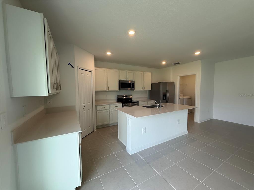 A kitchen with white cabinets, quartz countertops, a center island, and stainless steel appliances — 2528 ABSOLUTE AVENUE, HAINES CITY, FL