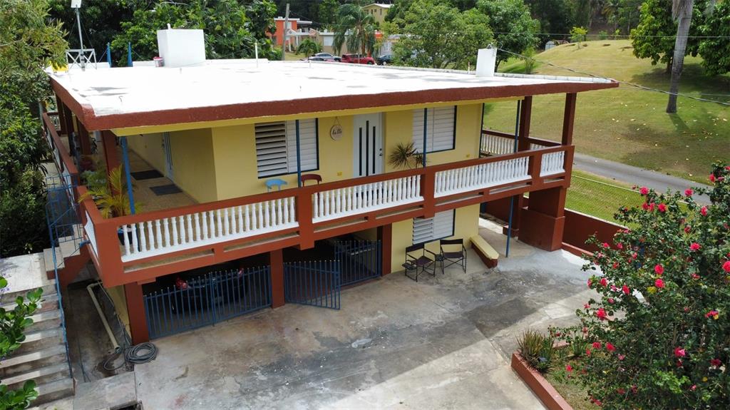 An elevated yellow house with a white roof, a balcony, and a ground-level gated carport — carr. 985 km 3.0 BO. FLORENCIO, FAJARDO, PR