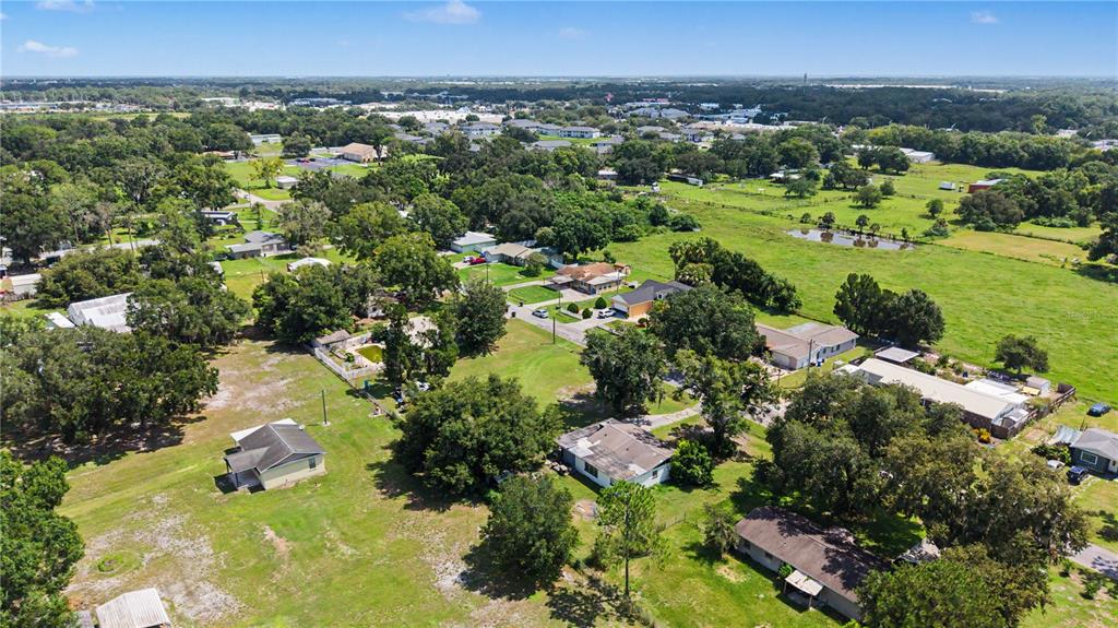 An aerial view shows several detached houses surrounded by trees and open grassy fields — 3015 DER ROAD, PLANT CITY, FL