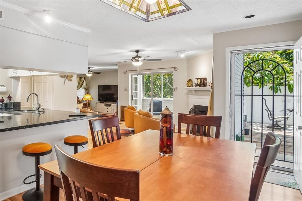 A dining area with a wooden table leads to a living room and an outdoor patio — 8350 SAVANNAH TRACE CIRCLE UNIT 1601, TAMPA, FL