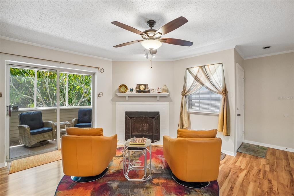 A living room features a fireplace, two orange chairs, a patterned rug, and sliding glass doors — 8350 SAVANNAH TRACE CIRCLE UNIT 1601, TAMPA, FL