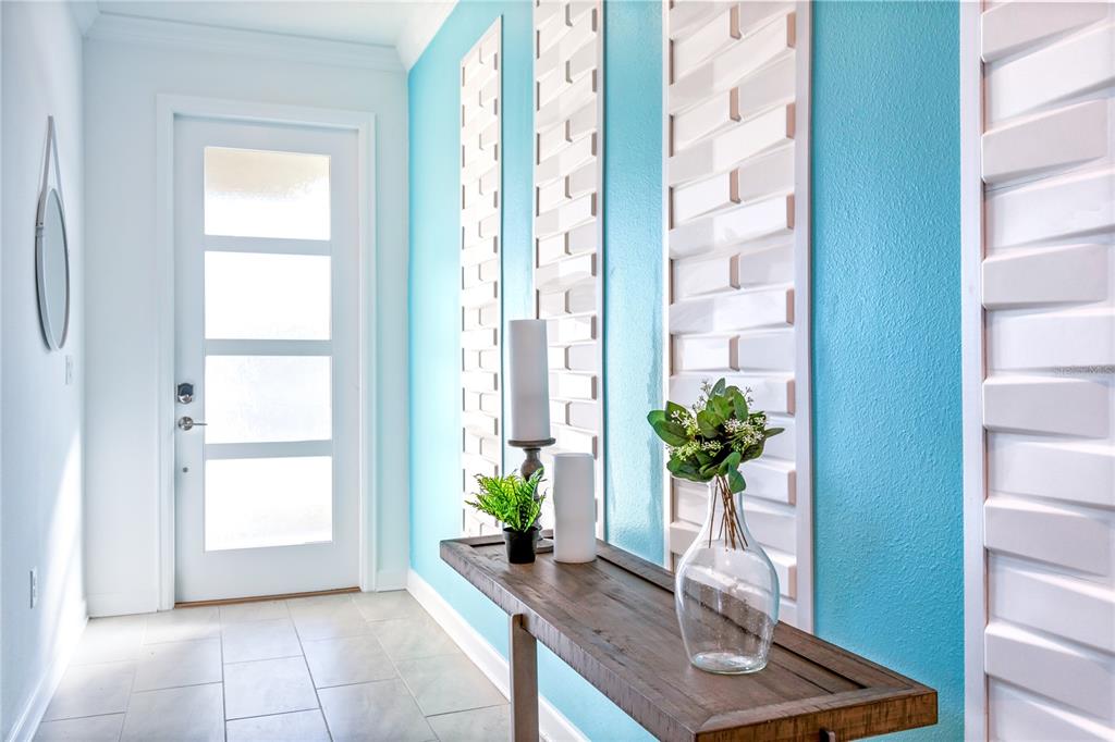 A bright entryway features a white door, blue walls with decorative panels, and a wooden console — 3032 PROTAGONIST STREET, KISSIMMEE, FL