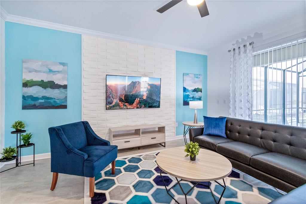 A living room features a white brick accent wall, blue walls, and a geometric rug — 3032 PROTAGONIST STREET, KISSIMMEE, FL