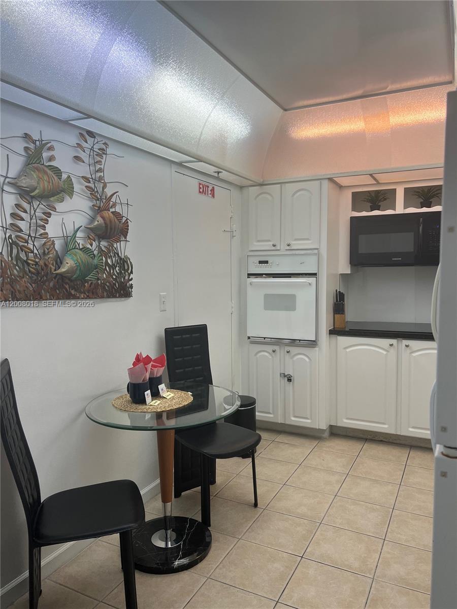 A kitchen features white cabinets, a wall oven, a microwave, and a small dining table — 3901 S Ocean Dr # 14T, Hollywood FL 33019, HOLLYWOOD, FL