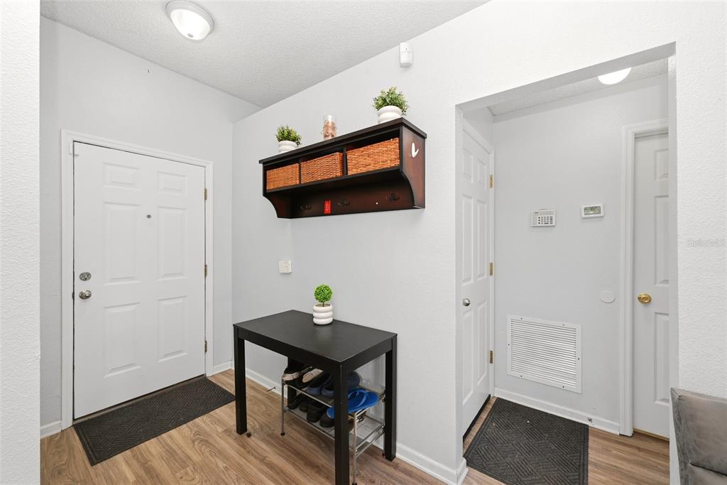 An entryway features a white door, a black console table with shoe storage, and wall shelving — 143 LAUREL RIDGE AVENUE, OCOEE, FL