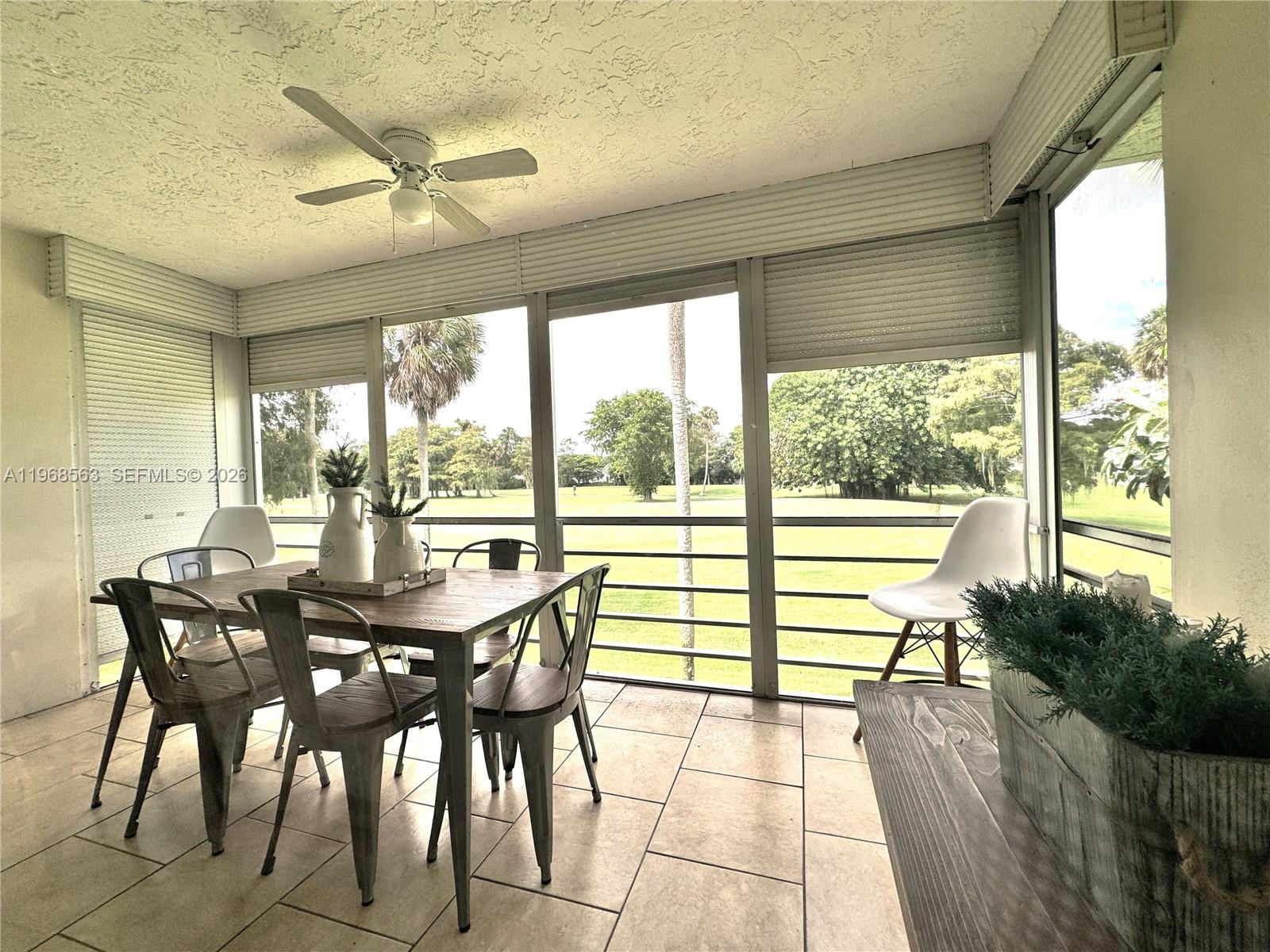 A screened-in patio features a dining set, tile flooring, and a view of a golf course — 901 W Cypress Ln # 201, Pompano Beach FL 33069, POMPANO BEACH, FL