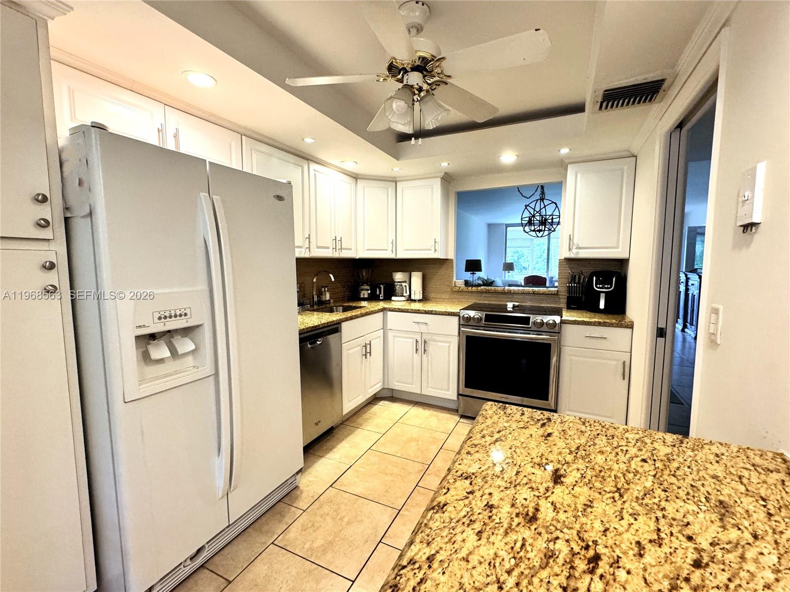 A kitchen features white cabinets, granite countertops, stainless steel appliances, and tile flooring — 901 W Cypress Ln # 201, Pompano Beach FL 33069, POMPANO BEACH, FL