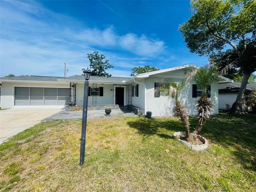 A single-story house with a gray roof, white exterior, and a paved front patio area — 999 ELEANOR AVENUE, DELTONA, FL