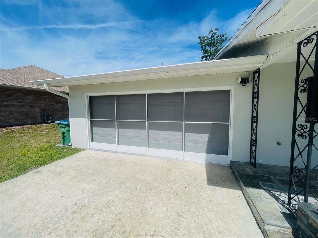 A concrete driveway leads to a garage with a four-panel sliding screen door — 999 ELEANOR AVENUE, DELTONA, FL