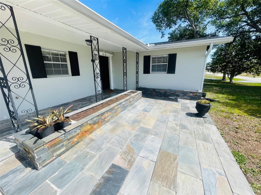 A front porch features slate tile flooring, a stone planter, and decorative wrought iron columns — 999 ELEANOR AVENUE, DELTONA, FL