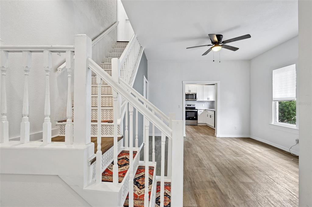 A staircase with a patterned runner leads upward next to a living area and kitchen — 1305 E 17TH AVENUE, TAMPA, FL