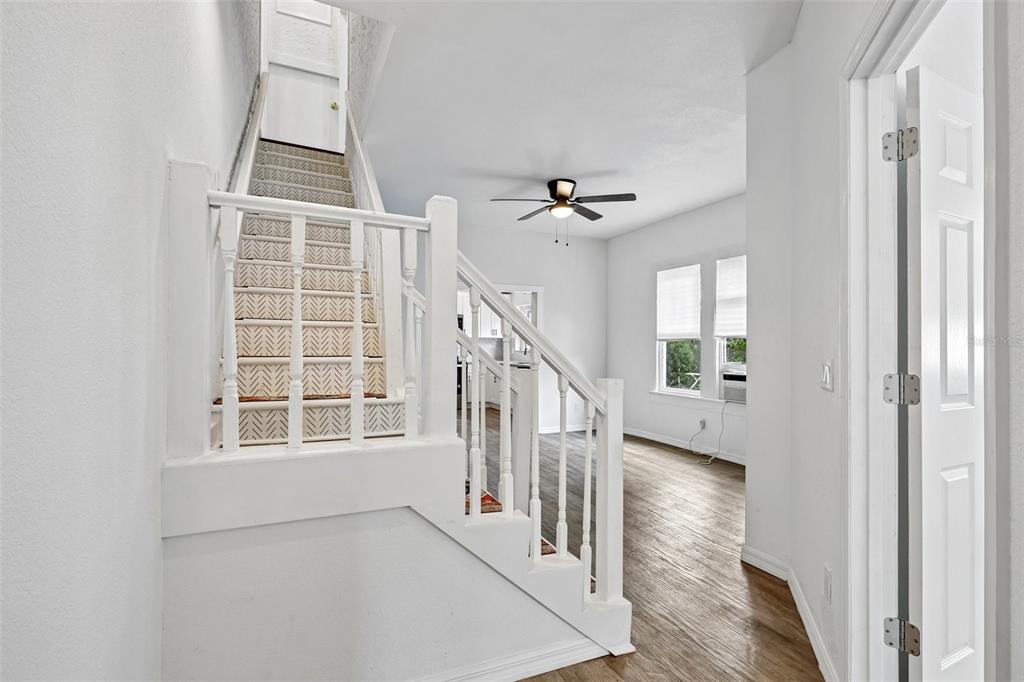 A white staircase with a patterned runner leads upward next to a bright living area — 1305 E 17TH AVENUE, TAMPA, FL