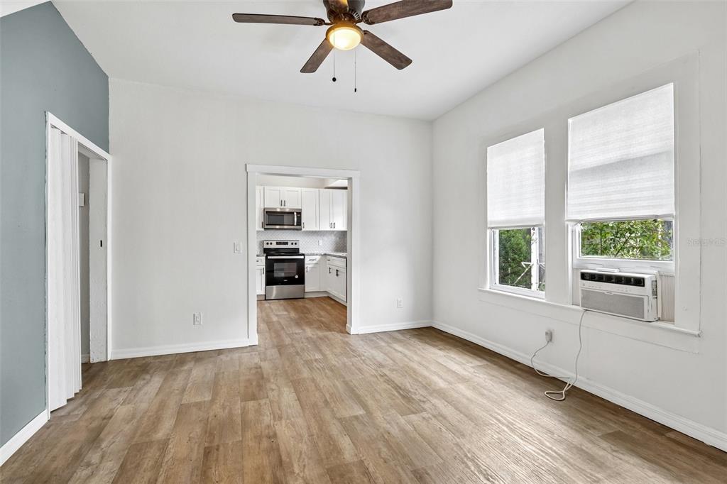 A living room with wood-look flooring, a ceiling fan, and a doorway leading to a kitchen — 1305 E 17TH AVENUE, TAMPA, FL