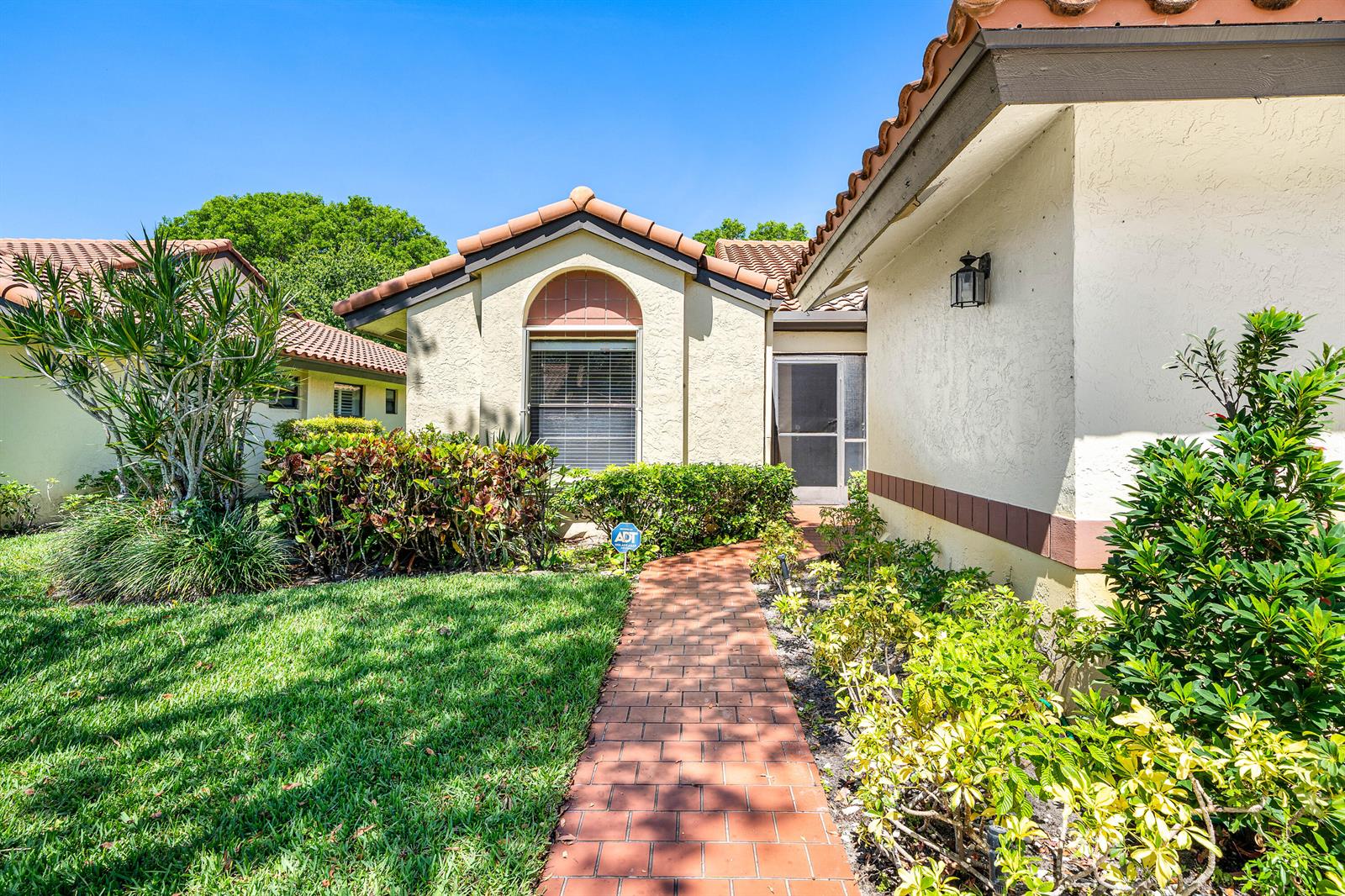 A brick walkway leads to the front entrance of a stucco home with tile roofing — 10069 Andrea Lane # A, Boynton Beach FL 33437, BOYNTON BEACH, FL