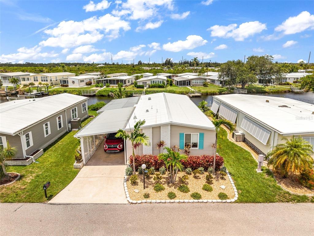 An aerial view of a single-story manufactured home with a carport and landscaped front yard — 114 MARTINIQUE ROAD, NORTH PORT, FL