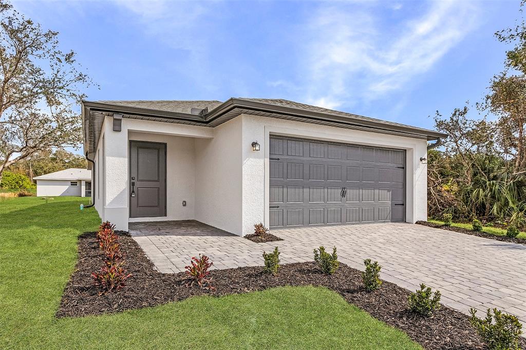 A single-story house with a white stucco exterior, a gray garage door, and a paved driveway — 2817 SNUG STREET, NORTH PORT, FL