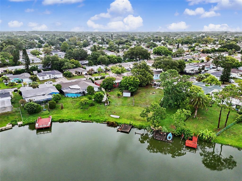 An aerial view shows a residential property with a large backyard and private boat docks — 9641 LAKESIDE LANE, PORT RICHEY, FL