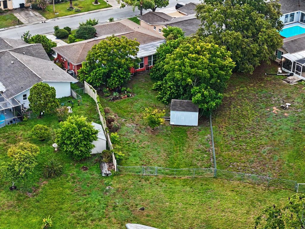 An aerial view shows a residential backyard with two sheds, trees, and a chain-link fence — 9641 LAKESIDE LANE, PORT RICHEY, FL