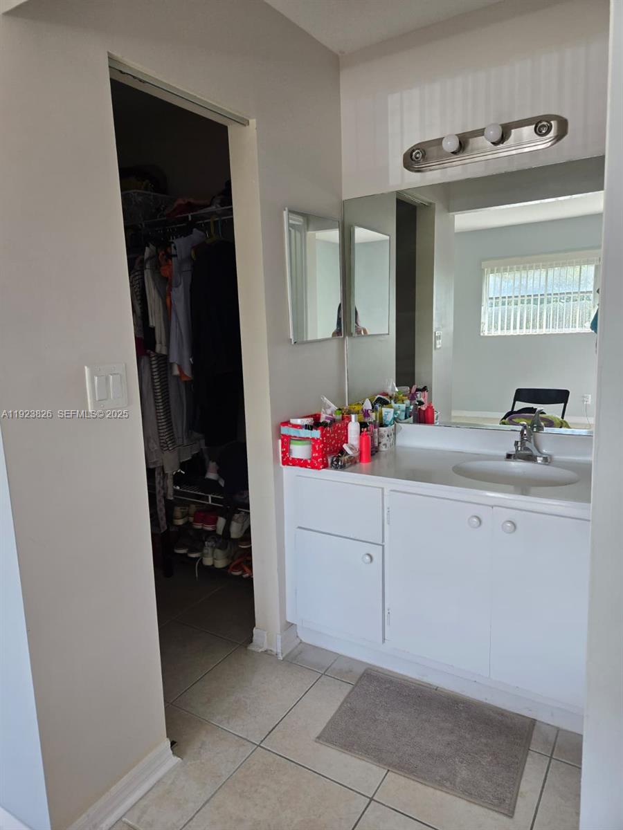 A bathroom vanity with a white cabinet and mirror sits next to an open closet — 7837 Golf Cir Dr # 310, Margate FL 33063, MARGATE, FL