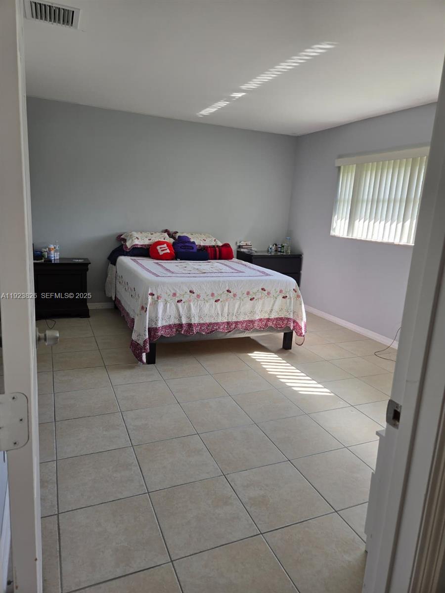 A bedroom features light gray walls, large beige floor tiles, and a bed with bedding — 7837 Golf Cir Dr # 310, Margate FL 33063, MARGATE, FL