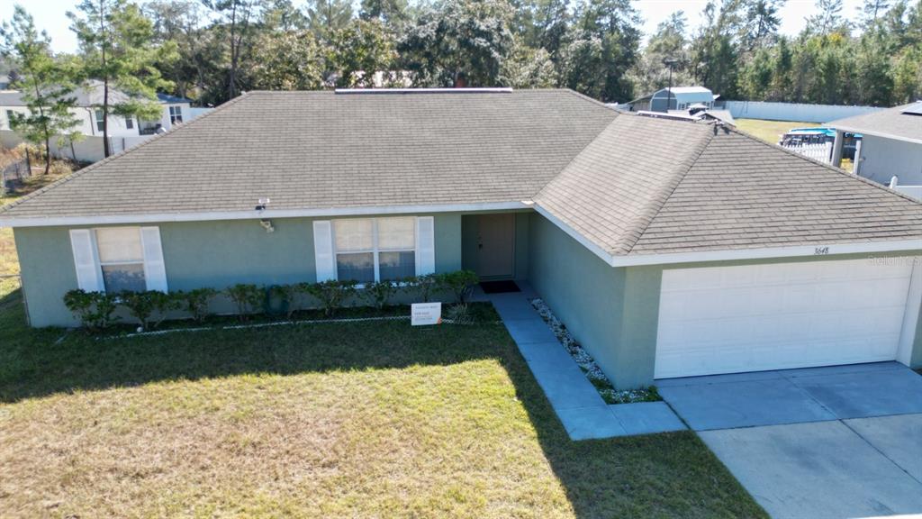 An aerial view shows a single-story house with a green exterior, shingled roof, and garage — 3648 SW 131ST PLACE ROAD, OCALA, FL