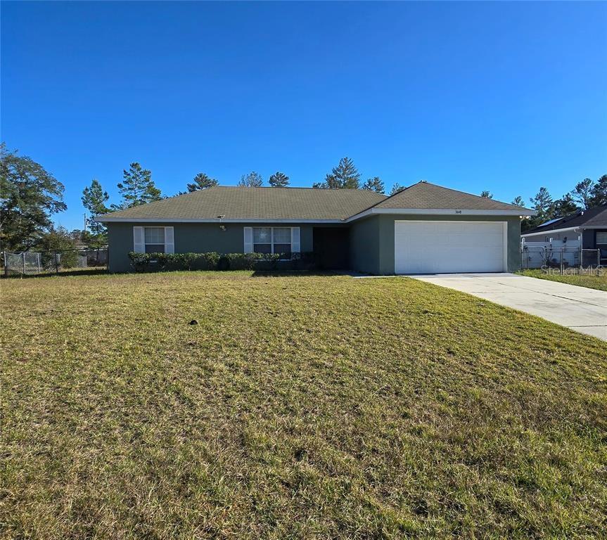A single-story house with a green exterior, a two-car garage, and a large front lawn — 3648 SW 131ST PLACE ROAD, OCALA, FL