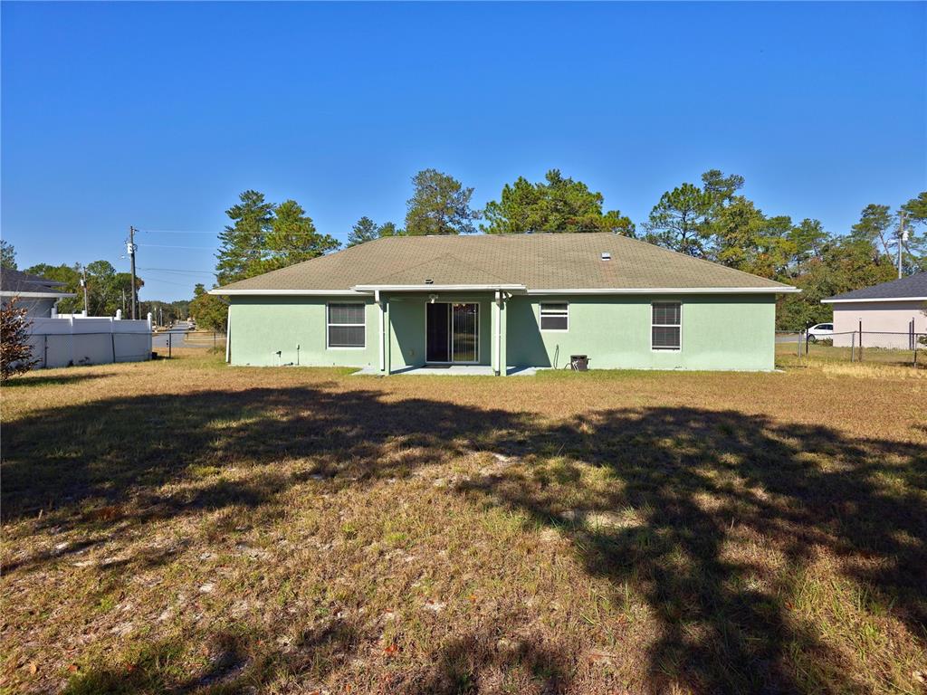 The rear exterior of a light green, single-story house with a covered patio — 3648 SW 131ST PLACE ROAD, OCALA, FL