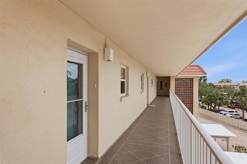 A view of a multi-story waterfront condominium building with a red circle highlighting the top-floor balcony — 1215 S PORTOFINO DRIVE UNIT 406, SARASOTA, FL